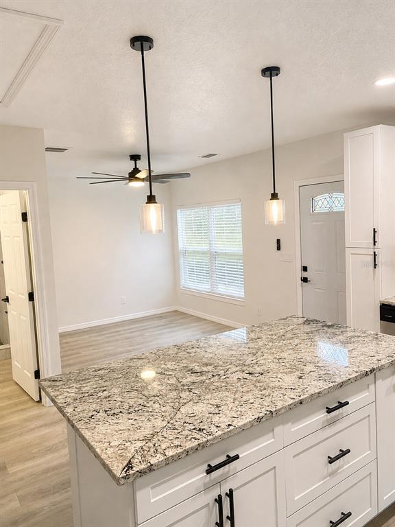A kitchen island with granite countertops sits in front of a dining area with pendant lights — 1710 W NORTH B STREET UNIT 2, TAMPA, FL