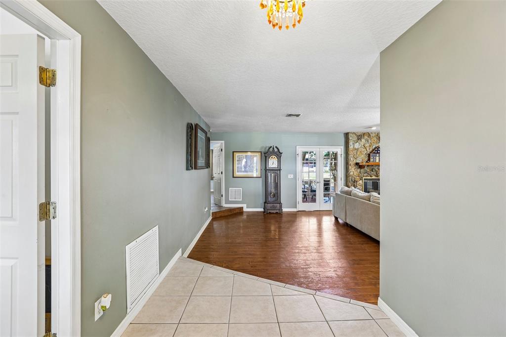 An entryway with tile flooring transitions into a living room featuring hardwood floors and a fireplace — 3131 N CANAL DRIVE, PALM HARBOR, FL