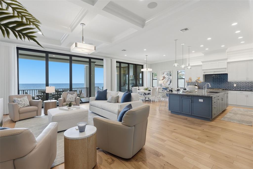 An open-concept living room and kitchen feature light wood floors, a blue island, and ocean views — 15908 GULF BOULEVARD, REDINGTON BEACH, FL
