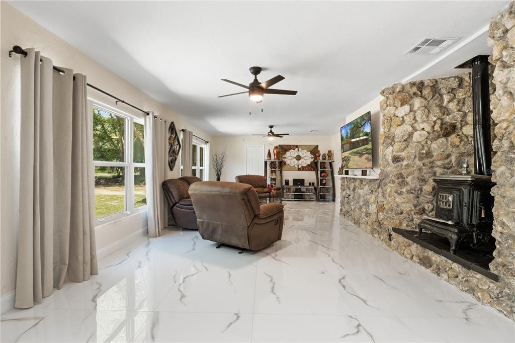A living room features white marble-look tile floors, a stone fireplace, and brown leather recliners — 67 COVE ROAD, INGLIS, FL