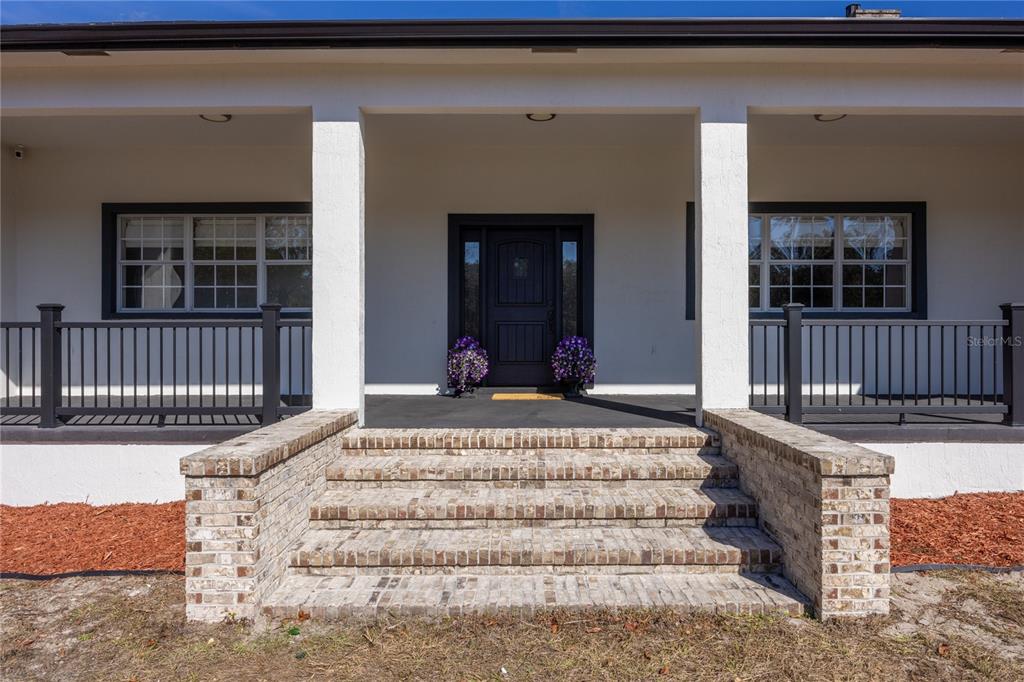 A front porch with brick steps, white columns, and a dark door leads to a house — 12456 155TH PLACE, LIVE OAK, FL
