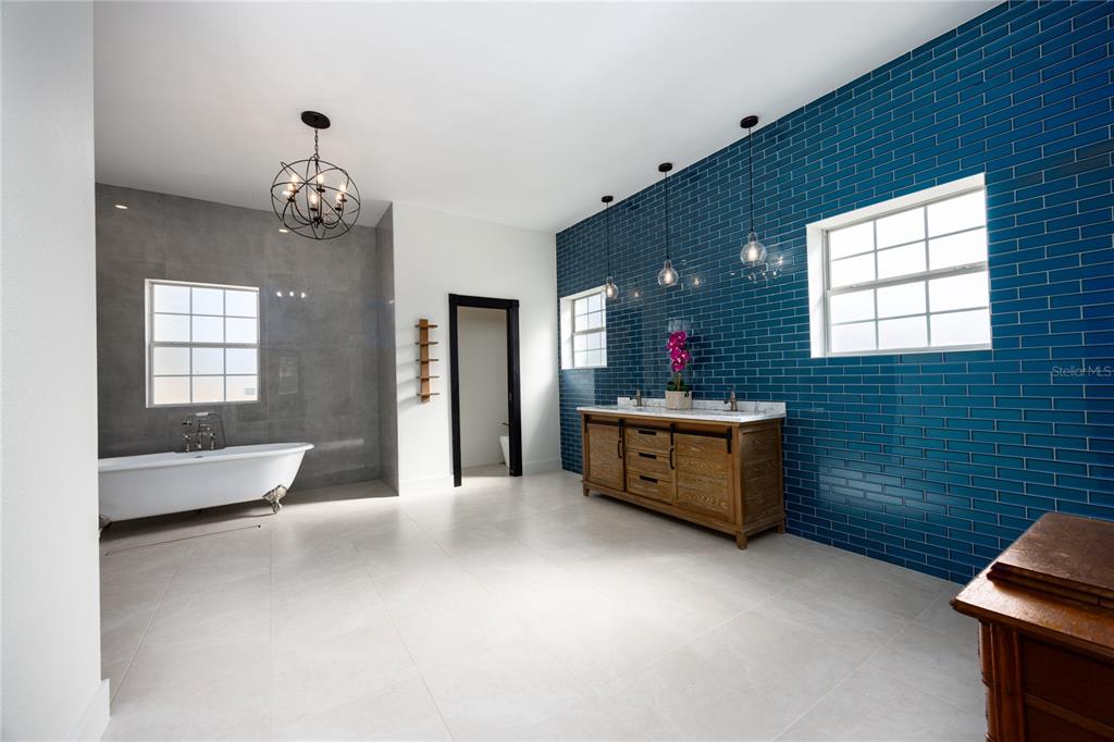 A bathroom features a freestanding tub, a wooden double vanity, and blue subway tile walls — 12456 155TH PLACE, LIVE OAK, FL
