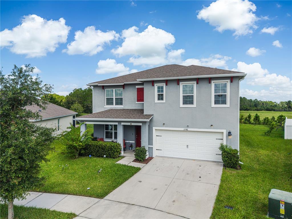 A two-story gray house with a white garage, red front door, and a grassy yard — 2786 HARMONIA HAMMOCK ROAD, ST CLOUD, FL
