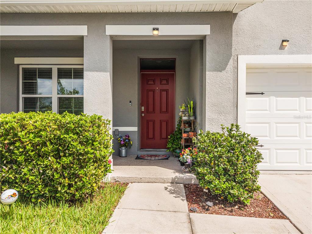 A front entrance features a red door, a concrete walkway, and two large green bushes — 2786 HARMONIA HAMMOCK ROAD, ST CLOUD, FL