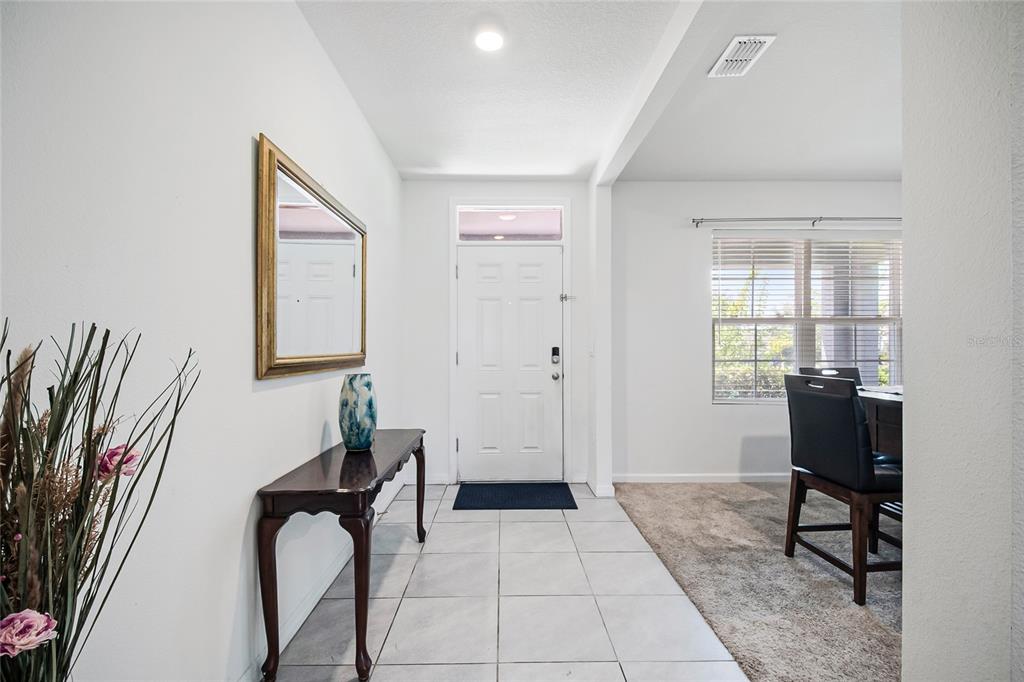 A tiled entryway features a console table, mirror, and a view into a carpeted dining area — 2786 HARMONIA HAMMOCK ROAD, ST CLOUD, FL