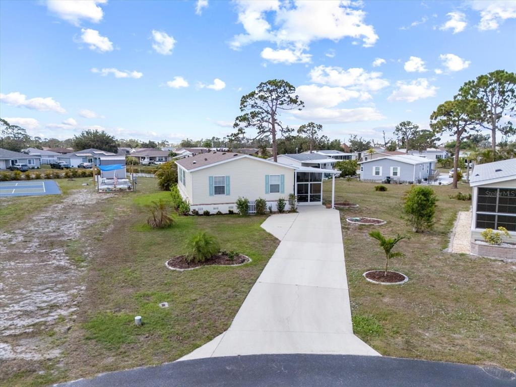 An aerial view of a light-colored manufactured home with a concrete driveway and surrounding yard — 9182 PINEHAVEN WAY, ENGLEWOOD, FL