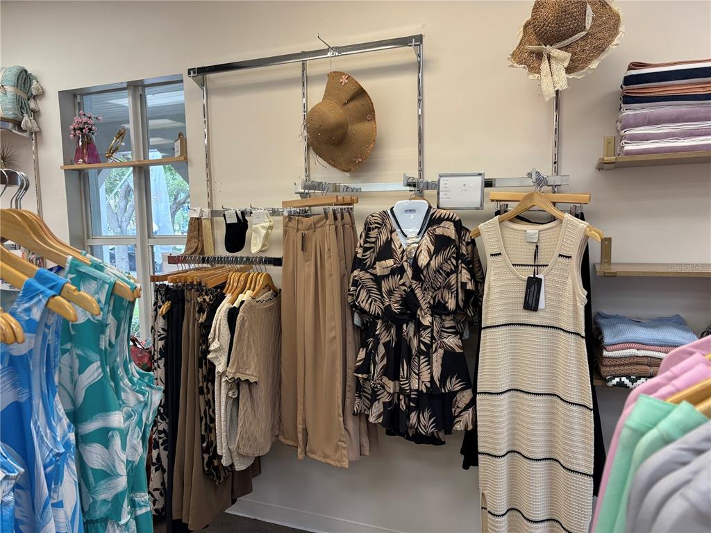 A retail clothing store features racks of apparel, hanging hats, and shelves with folded garments — 301 W BAY DRIVE UNIT 5, LARGO, FL