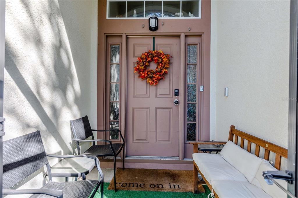 A front porch features a mauve door with a wreath, two chairs, and a bench — 6803 GUILFORD CREST DRIVE, APOLLO BEACH, FL