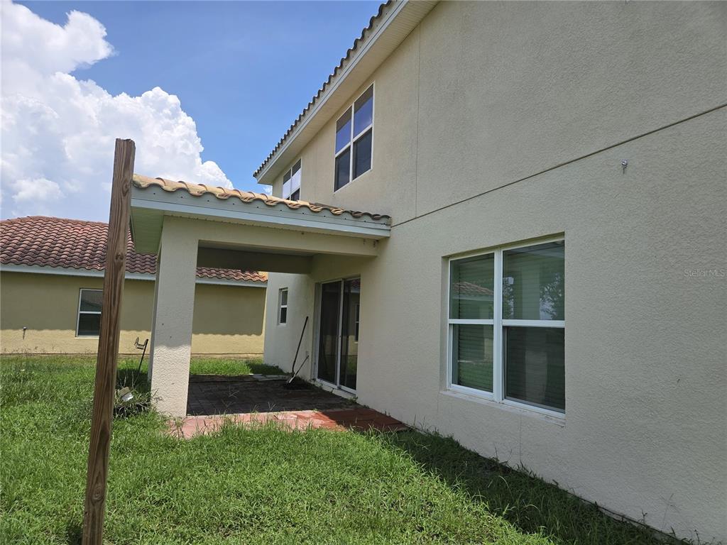 The exterior of a two-story house features a covered patio and a grassy backyard — 3872 CARRICK BEND DRIVE, KISSIMMEE, FL