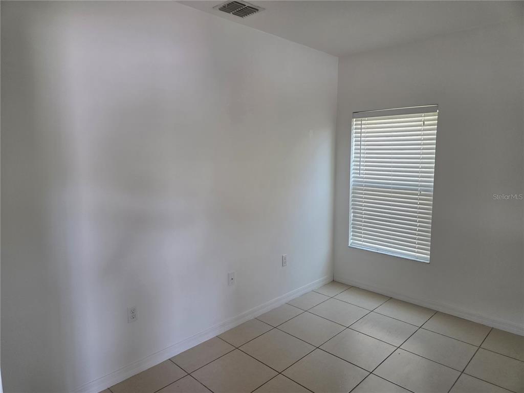 An empty room features white walls, light-colored floor tiles, and a single window with blinds — 3872 CARRICK BEND DRIVE, KISSIMMEE, FL