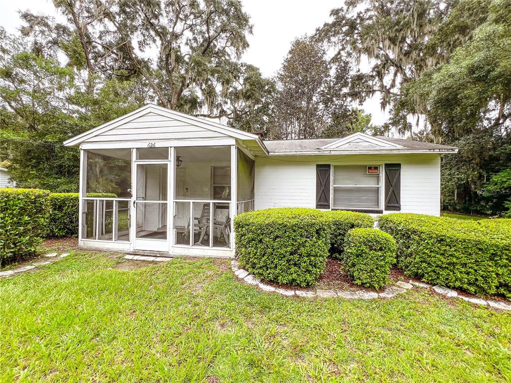 A white single-story house features a screened-in front porch and manicured hedges in the yard — 626 NW 31ST PLACE, GAINESVILLE, FL