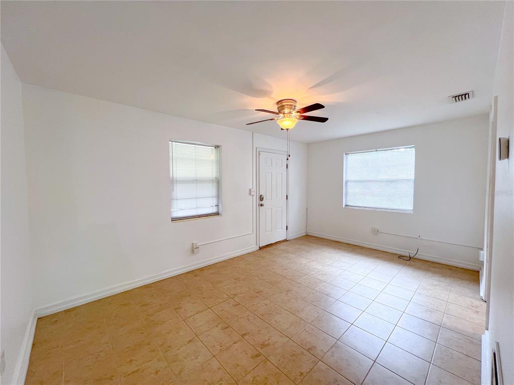 An empty room with white walls, tan tile flooring, a ceiling fan, and two windows — 626 NW 31ST PLACE, GAINESVILLE, FL