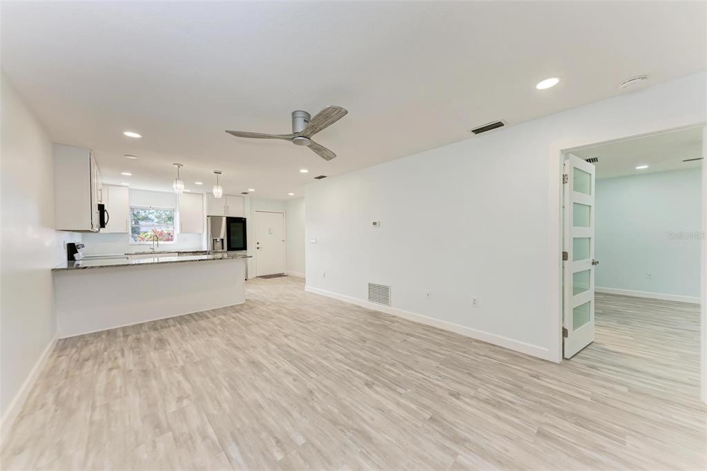 A bright, open-concept living area features light wood-look flooring, a kitchen island, and recessed lighting — 390 301 BOULEVARD W UNIT 8C, BRADENTON, FL