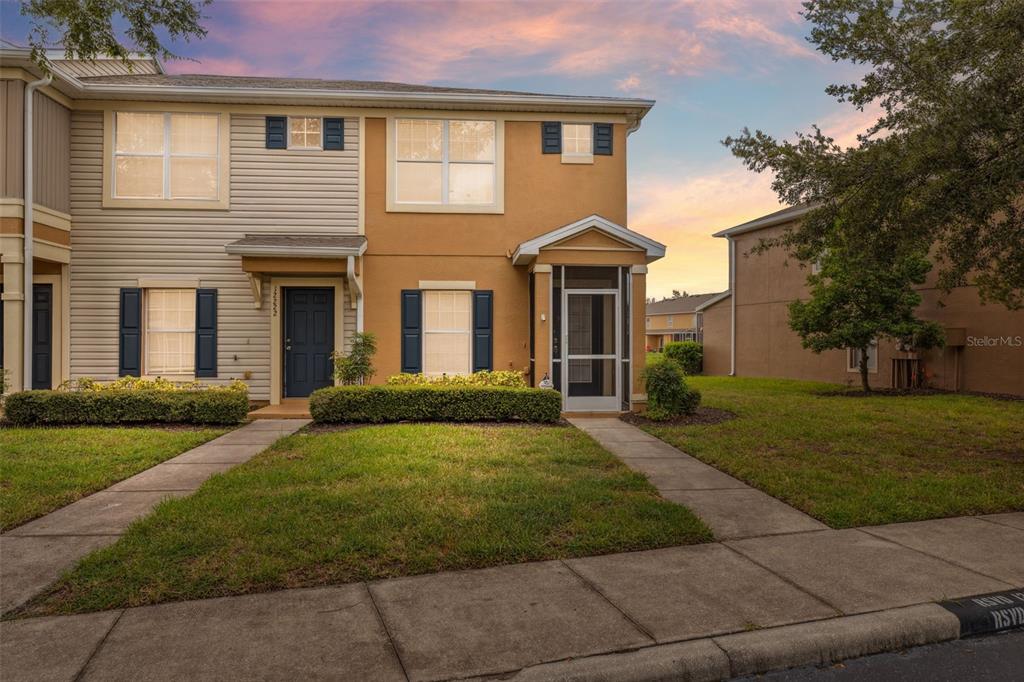 A two-story townhouse with tan siding and stucco exterior features a front porch and walkway — 12224 FOXMOOR PEAK DRIVE, RIVERVIEW, FL