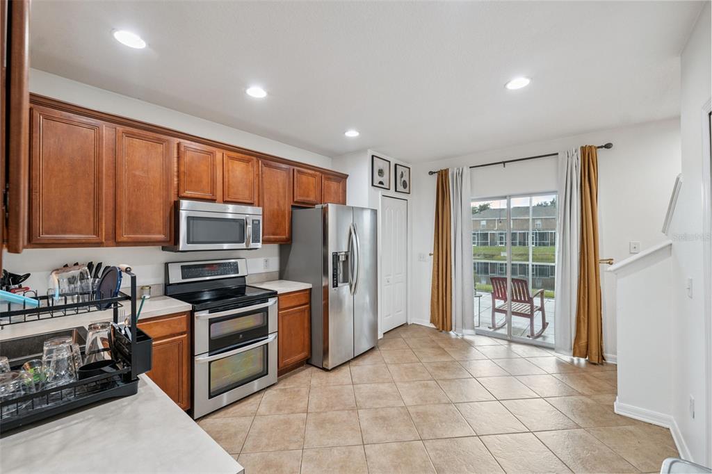 A kitchen with wood cabinets, stainless steel appliances, tile flooring, and a sliding glass door — 12224 FOXMOOR PEAK DRIVE, RIVERVIEW, FL