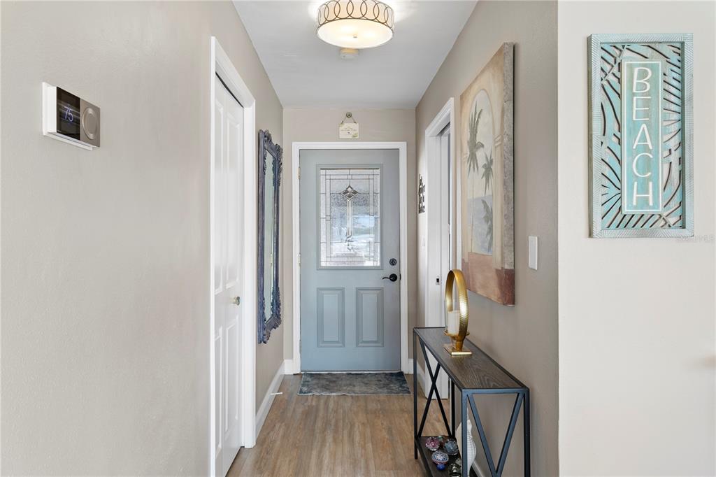 A light-filled entryway features a blue front door, wood-look flooring, and a console table — 3142 W VINA DEL MAR BOULEVARD, ST PETE BEACH, FL
