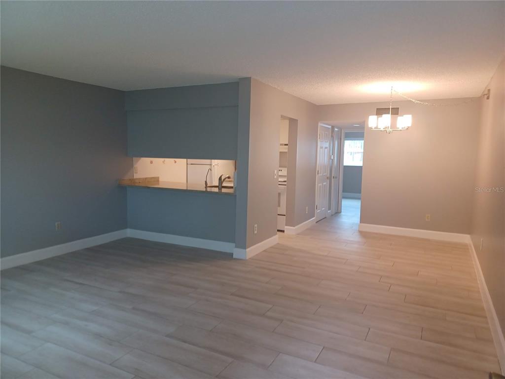 A swimming pool area with lounge chairs, tables, umbrellas, and a multi-story apartment building — 2525 W BAY DRIVE UNIT A12, BELLEAIR BLUFFS, FL