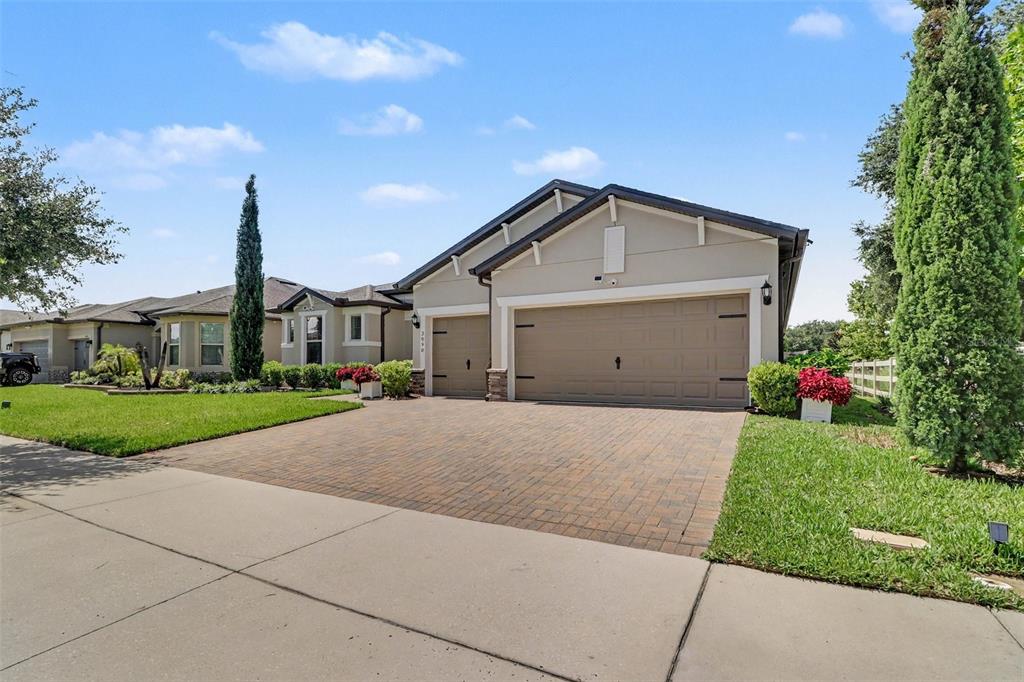 A beige single-story house features a three-car garage and a paved driveway — 2898 MATERA DRIVE, ST CLOUD, FL