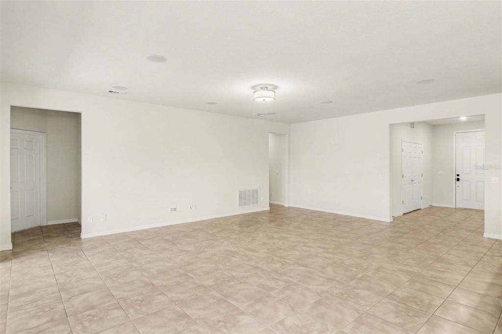 A spacious, empty room with light-colored tile flooring, white walls, and a central ceiling light — 2898 MATERA DRIVE, ST CLOUD, FL