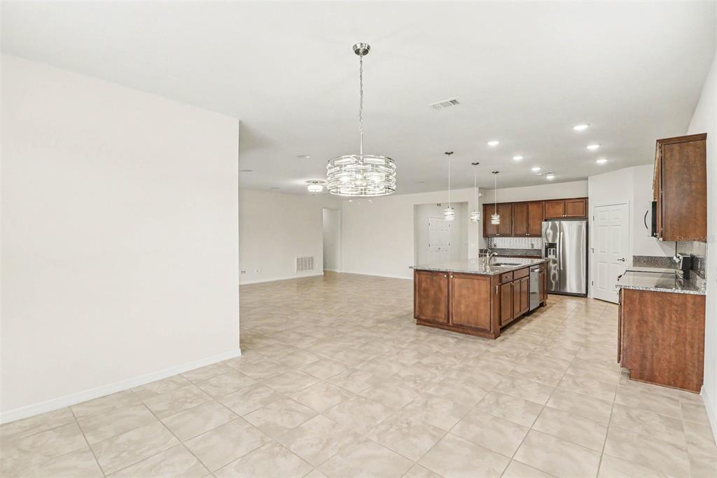 An open-concept kitchen and living area features tile flooring, dark wood cabinetry, and granite countertops — 2898 MATERA DRIVE, ST CLOUD, FL
