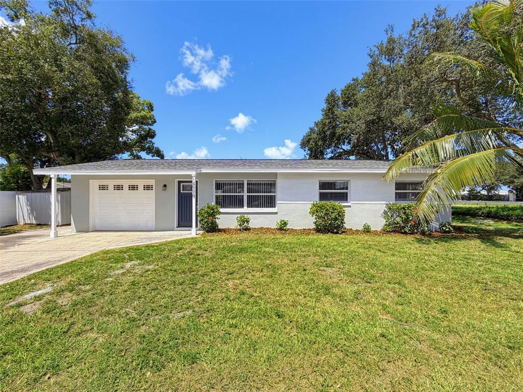 A single-story house with a white brick exterior, a one-car garage, and a front lawn — 14998 MOCKINGBIRD LANE, CLEARWATER, FL