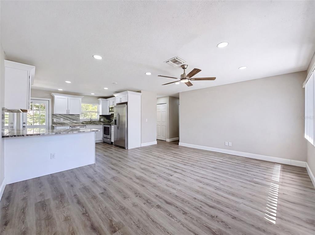 A kitchen with white cabinets and stainless steel appliances opens into a spacious living area — 14998 MOCKINGBIRD LANE, CLEARWATER, FL
