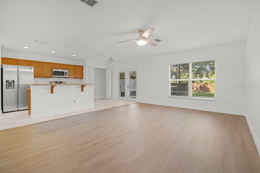 An open-concept kitchen and living area featuring light wood flooring and a breakfast bar — 2016 PORTCASTLE CIRCLE, WINTER GARDEN, FL