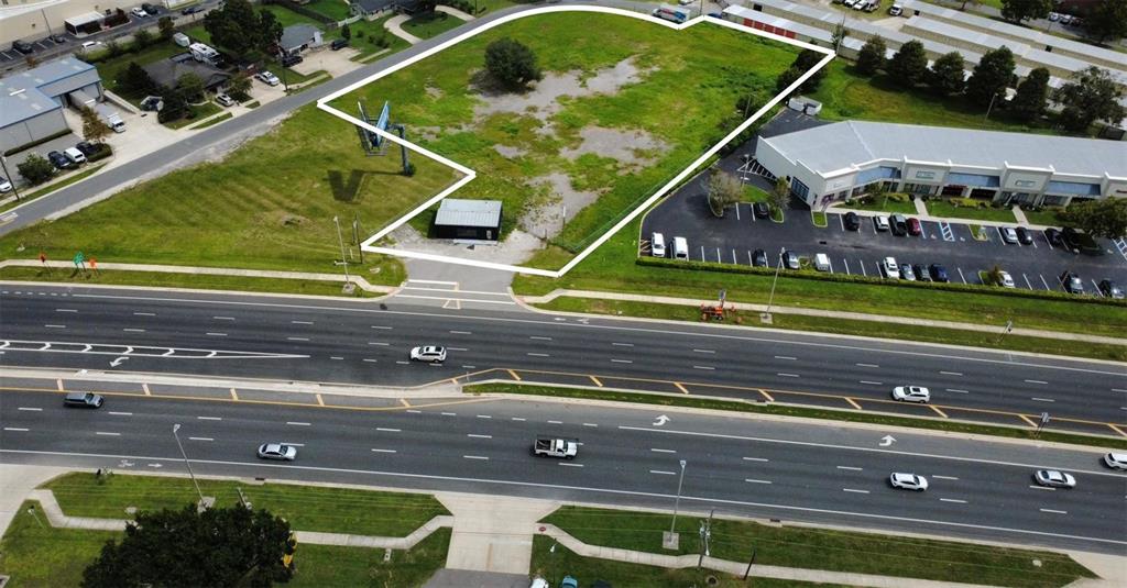 An aerial view shows a vacant, grass-covered commercial lot outlined in white next to a road — 2543 E IRLO BRONSON MEMORIAL HIGHWAY, KISSIMMEE, FL