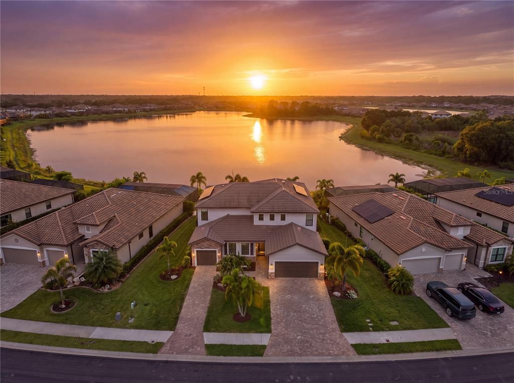 An aerial view of a two-story house with a tile roof facing a large lake — 17618 POLO TRAIL, BRADENTON, FL