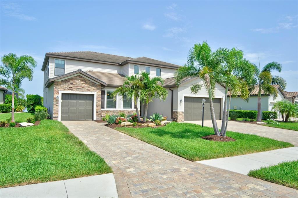 A two-story house with a stone facade, two garages, and palm trees in the front yard — 17618 POLO TRAIL, BRADENTON, FL