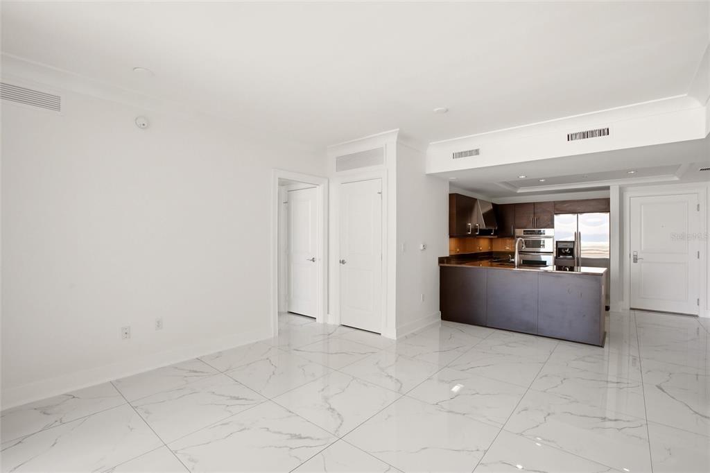 An open-concept living area features white marble-look tile floors and a modern kitchen with dark cabinetry — 1350 MAIN STREET UNIT 707, SARASOTA, FL