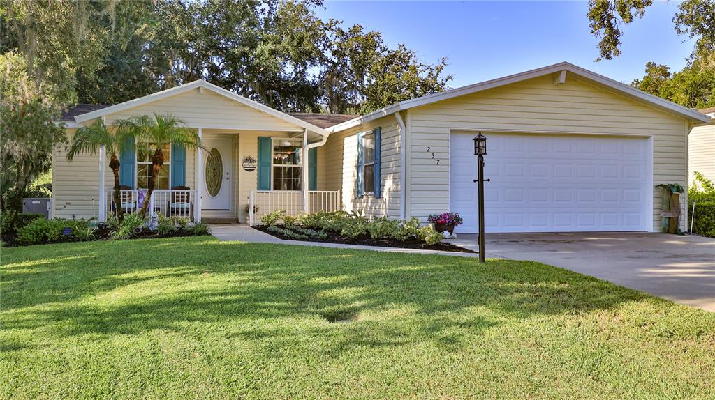 A single-story house with yellow siding, a two-car garage, and a front porch — 237 NAVAJO DRIVE, OAK HILL, FL