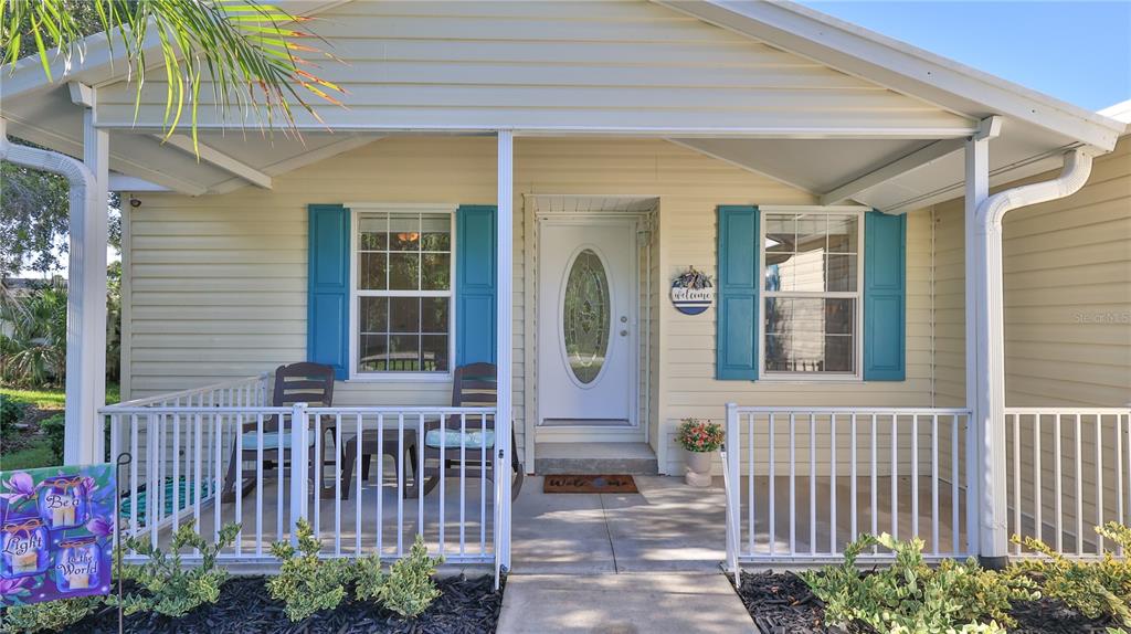 The exterior of a house features a covered front porch with white railings and blue shutters — 237 NAVAJO DRIVE, OAK HILL, FL