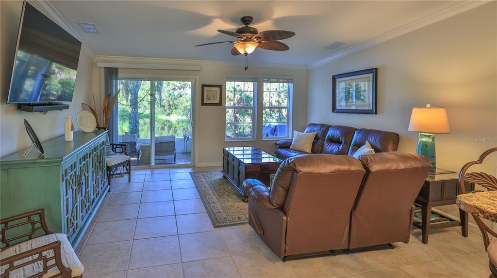 A living room with tile floors, a leather sofa, and a sliding door to a patio — 237 NAVAJO DRIVE, OAK HILL, FL