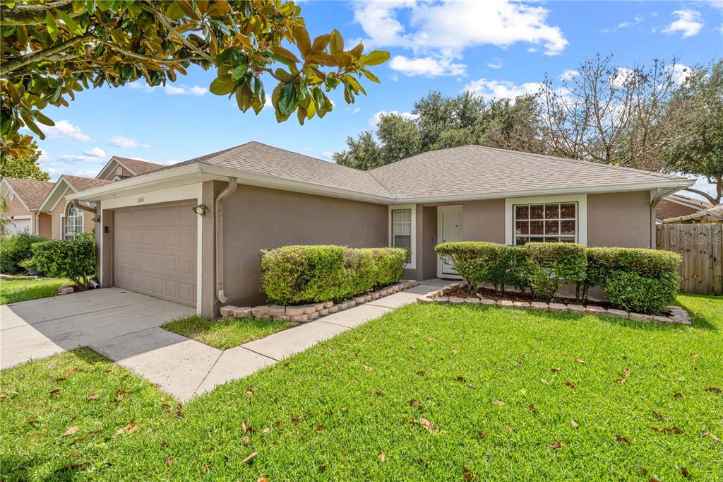 A single-story house with a tan exterior, a two-car garage, and a landscaped front yard — 10806 BROWN TROUT CIRCLE, ORLANDO, FL