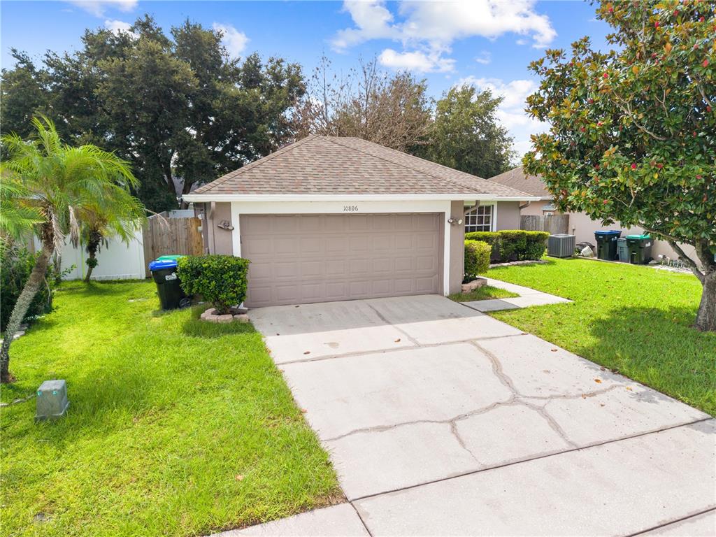 A single-story house exterior features a two-car garage, a concrete driveway, and a grassy yard — 10806 BROWN TROUT CIRCLE, ORLANDO, FL