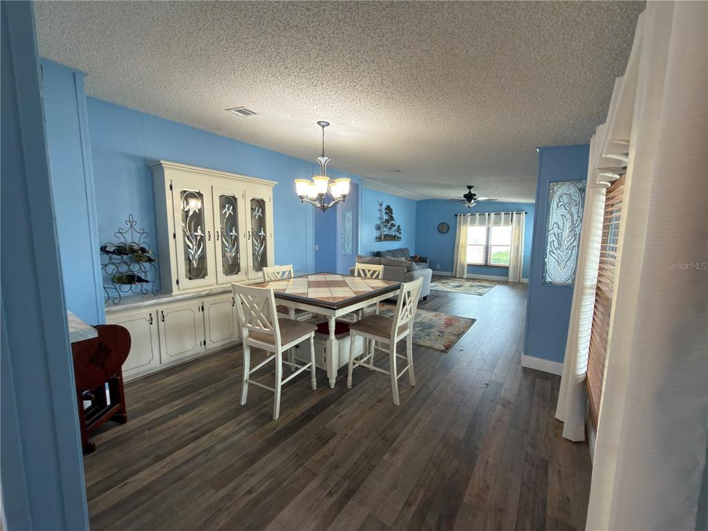 A living room with blue walls, wood-look flooring, a ceiling fan, and two gray sofas — 141 VICTORIA DRIVE, HAINES CITY, FL