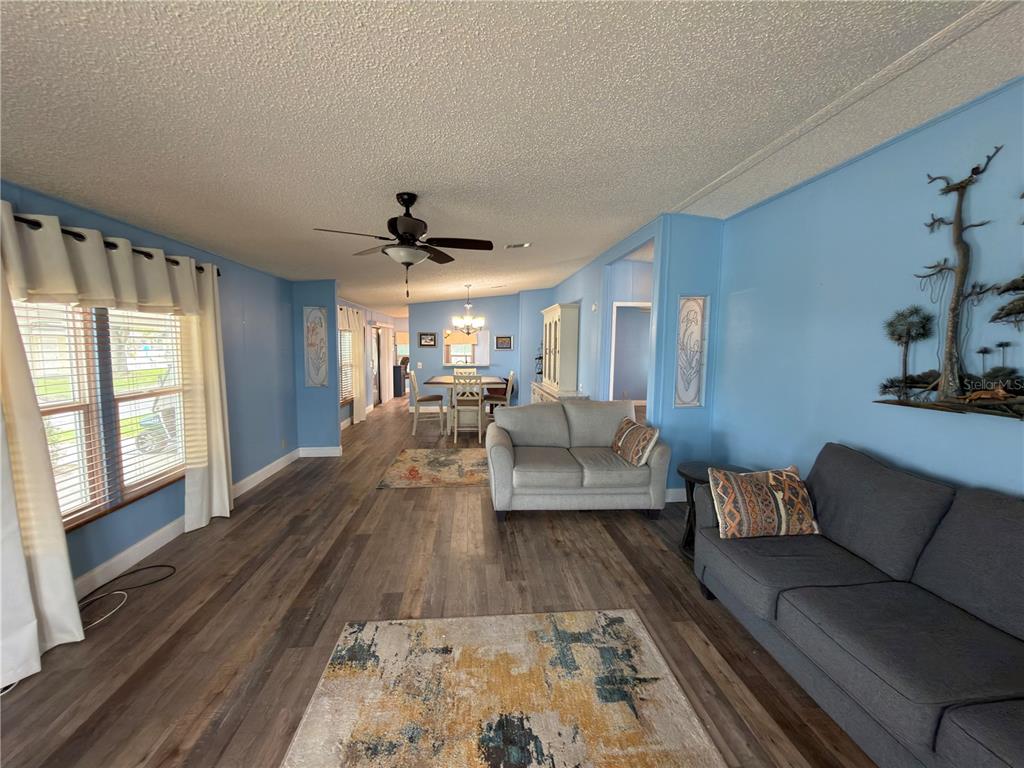 A living room features blue walls, wood-look flooring, a ceiling fan, and two sofas — 141 VICTORIA DRIVE, HAINES CITY, FL