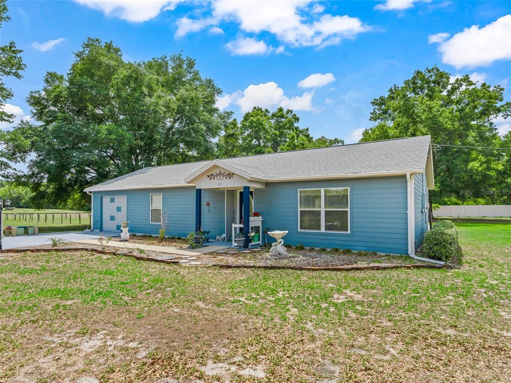 A blue, single-story house with a front porch and a large, grassy yard — 967 E HIGHWAY 316, CITRA, FL