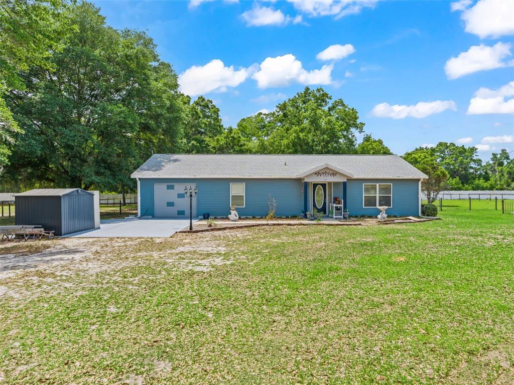 A blue single-story house with a gray roof sits on a grassy lot — 967 E HIGHWAY 316, CITRA, FL