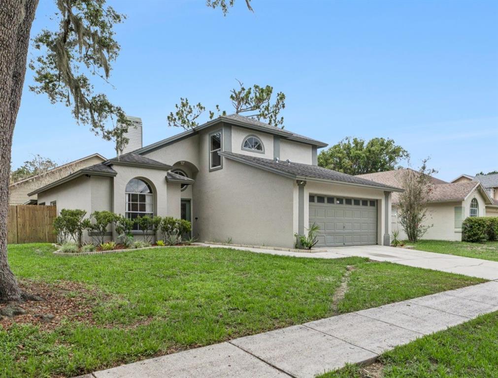 A two-story house with a gray garage, stucco exterior, and a front lawn — 4017 QUAIL BRIAR DRIVE, VALRICO, FL