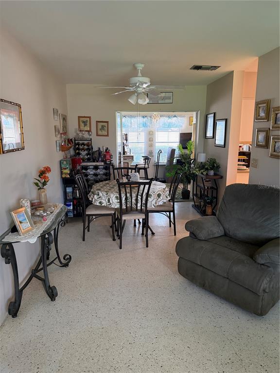 A dining area features a round table, chairs, a ceiling fan, and a nearby recliner — 3190 REGATTA CIRCLE, SARASOTA, FL