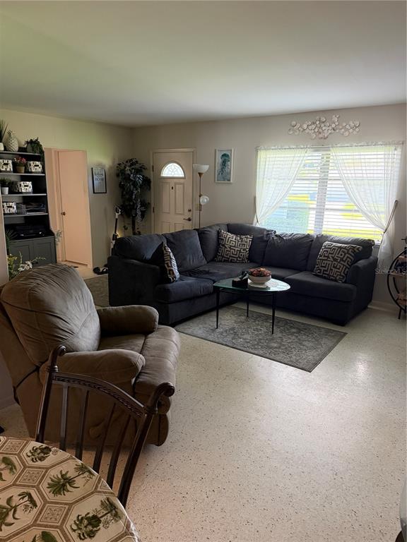 A living room features a dark sectional sofa, a recliner, and light-colored terrazzo flooring — 3190 REGATTA CIRCLE, SARASOTA, FL