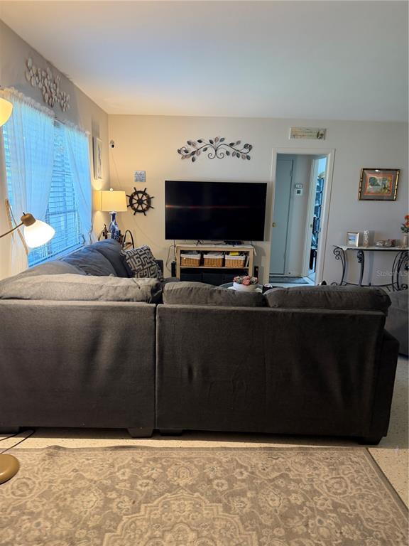 A living room features a large gray sectional sofa facing a wall-mounted television — 3190 REGATTA CIRCLE, SARASOTA, FL