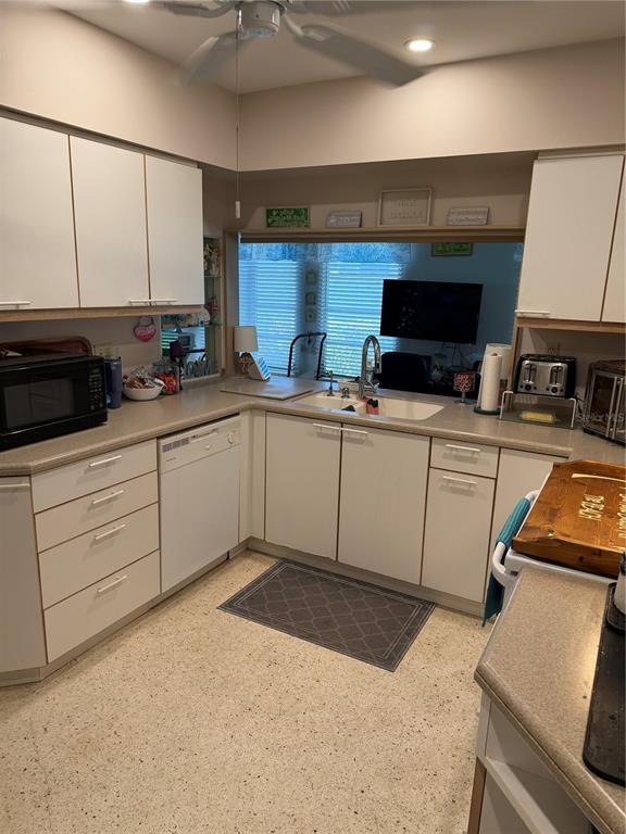 A kitchen features white cabinets, laminate countertops, a double sink, and speckled flooring — 3190 REGATTA CIRCLE, SARASOTA, FL