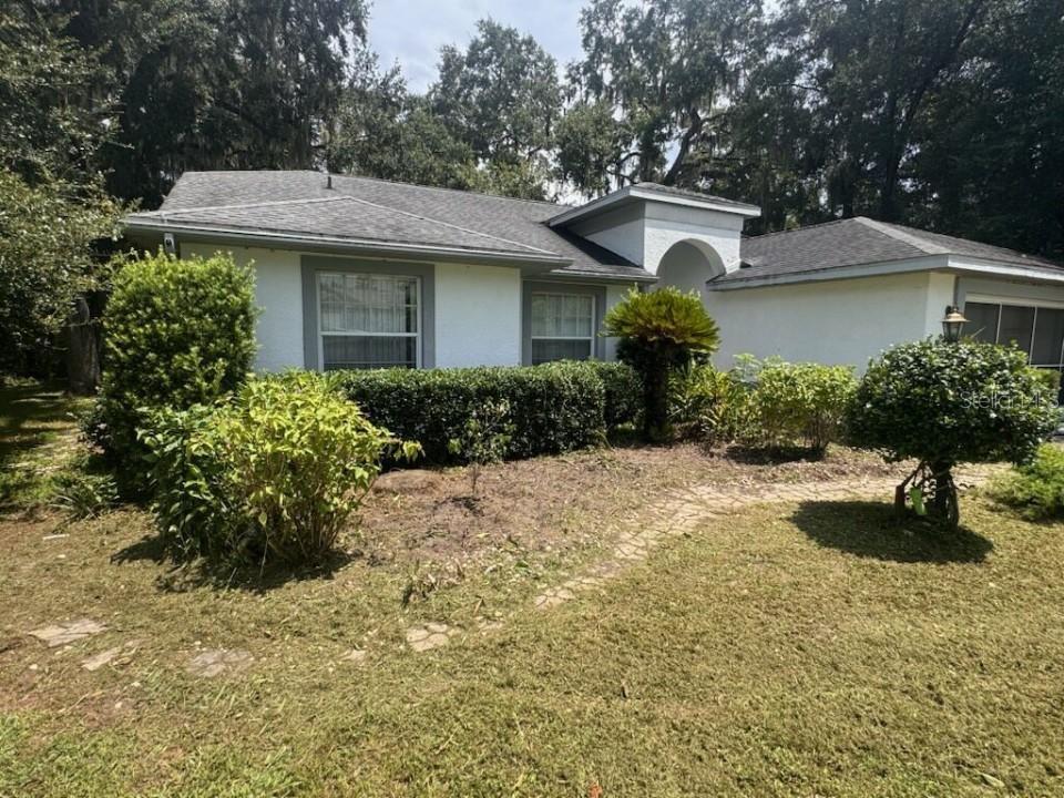 A single-story white house with a gray roof, arched entryway, and landscaped front yard — 2901 N ATTEBURY POINT, HERNANDO, FL