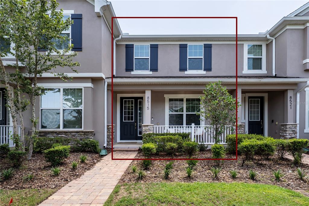 A two-story townhouse exterior features a covered front porch, dark shutters, and a paved walkway — 8515 VEDDER LN, ORLANDO, FL