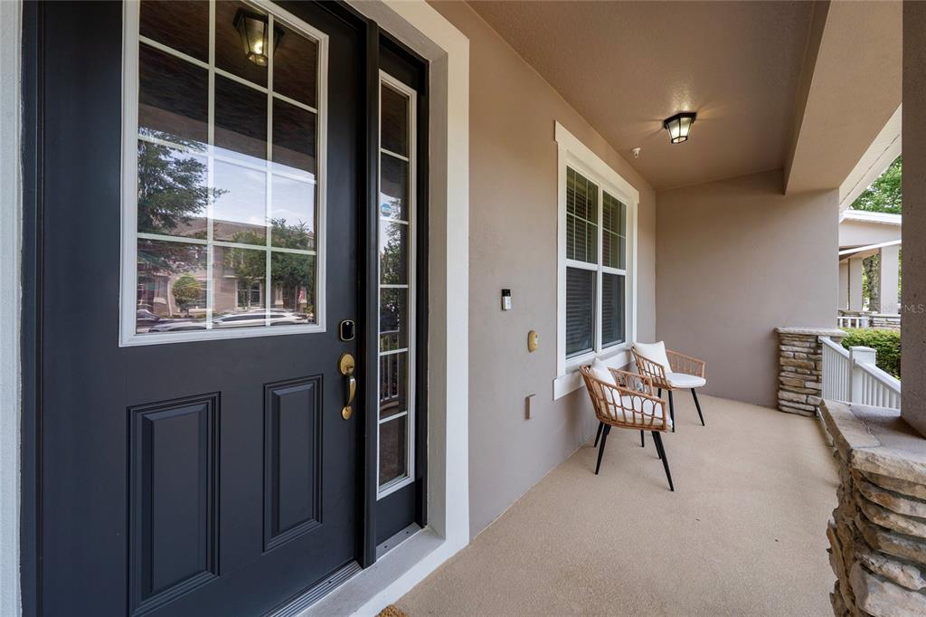 A covered front porch features a dark gray door, two wicker chairs, and stone accents — 8515 VEDDER LN, ORLANDO, FL