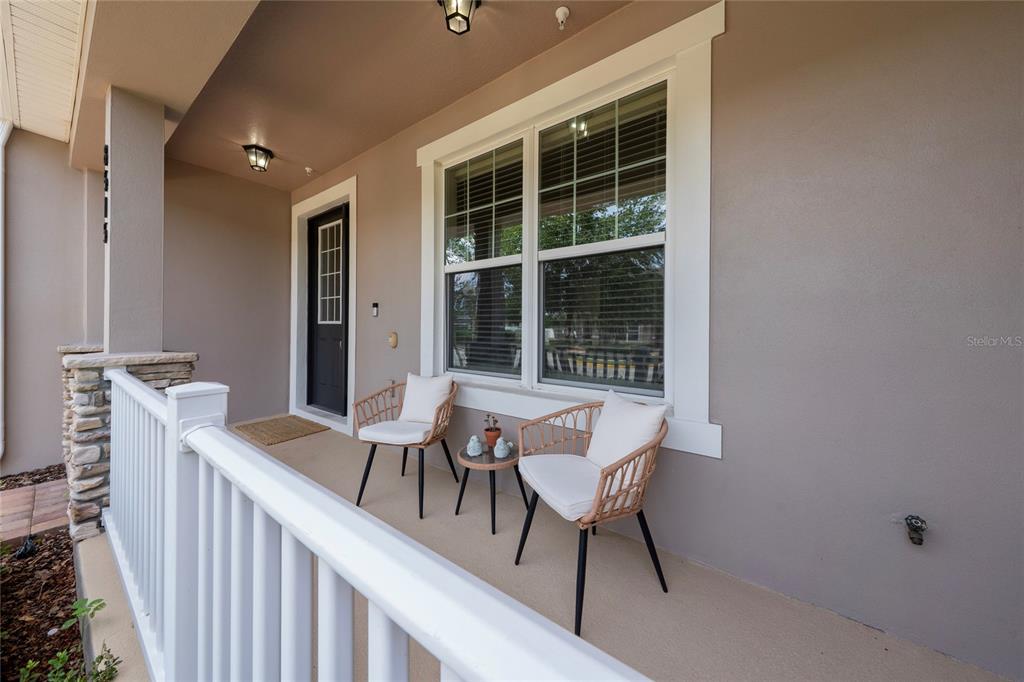 A covered front porch features two wicker chairs, a small table, and a black door — 8515 VEDDER LN, ORLANDO, FL