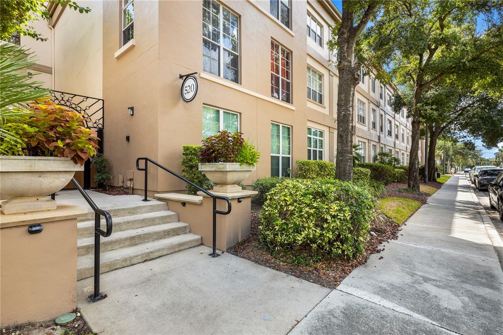 A tan multi-story apartment building exterior features concrete stairs leading to an entrance with planters — 520 S ARMENIA AVENUE UNIT 1229E, TAMPA, FL